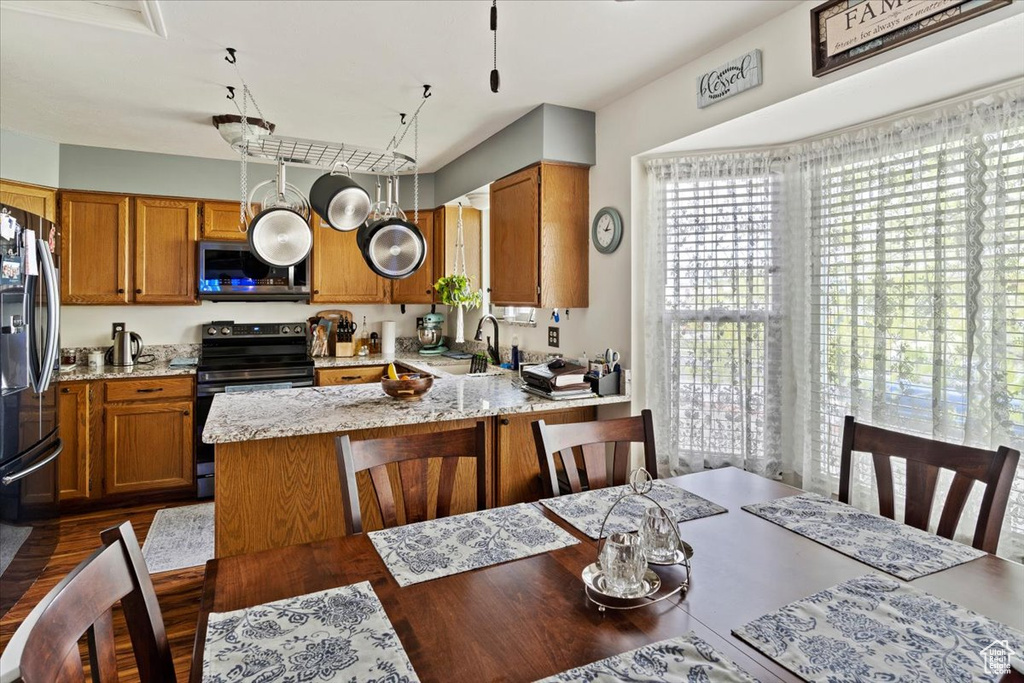 Kitchen with a sink, stainless steel microwave, black fridge, brown cabinets, and electric range oven