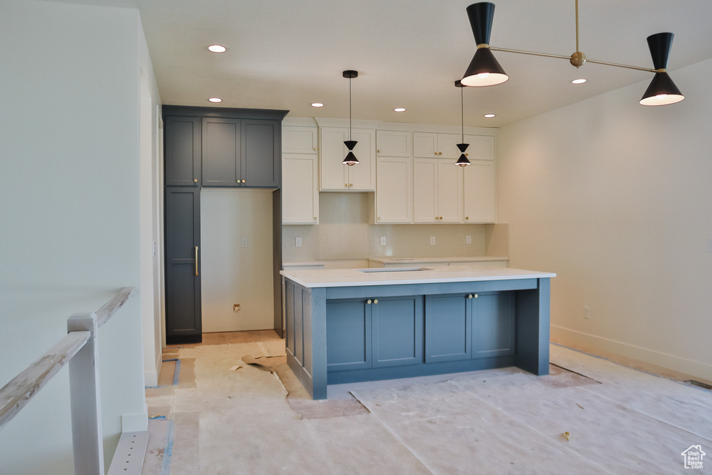Kitchen with recessed lighting, hanging light fixtures, baseboards, a center island, and light countertops