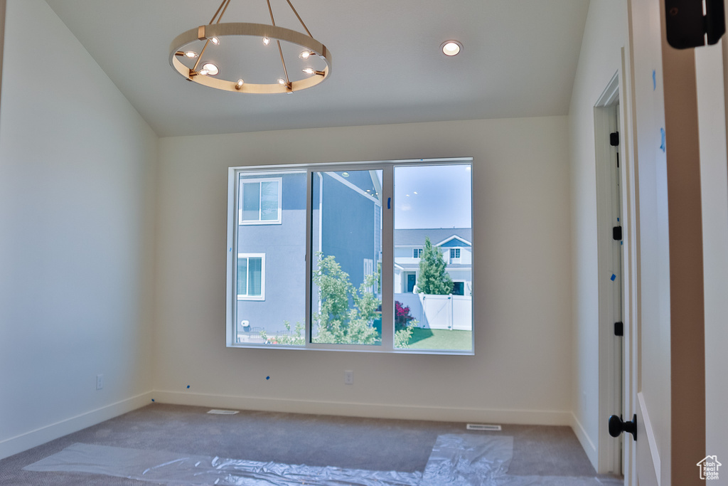 Spare room featuring carpet flooring, a chandelier, baseboards, and vaulted ceiling