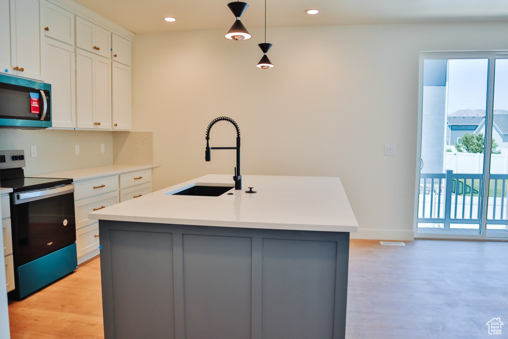 Kitchen with stainless steel appliances, a sink, healthy amount of natural light, an island with sink, and recessed lighting