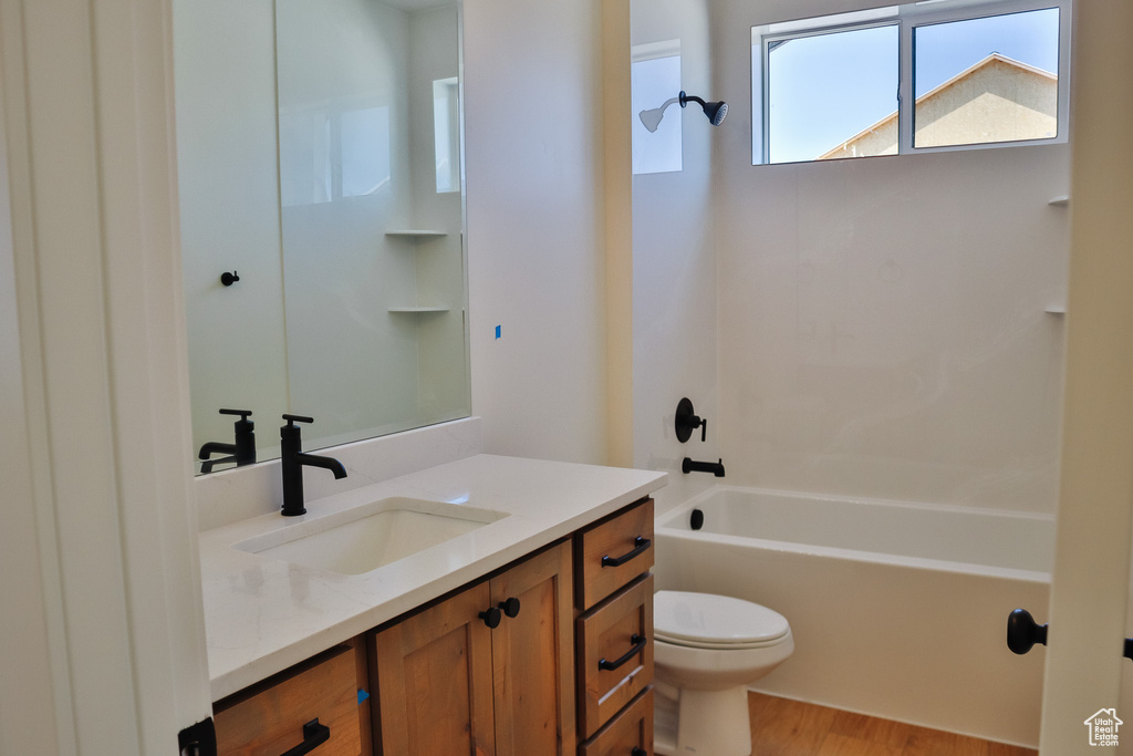 Full bath featuring vanity, toilet, wood finished floors, and bathtub / shower combination