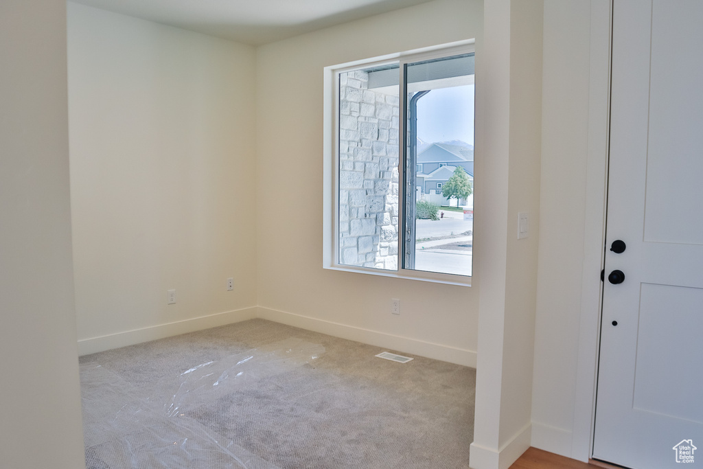 Unfurnished room with baseboards and light colored carpet