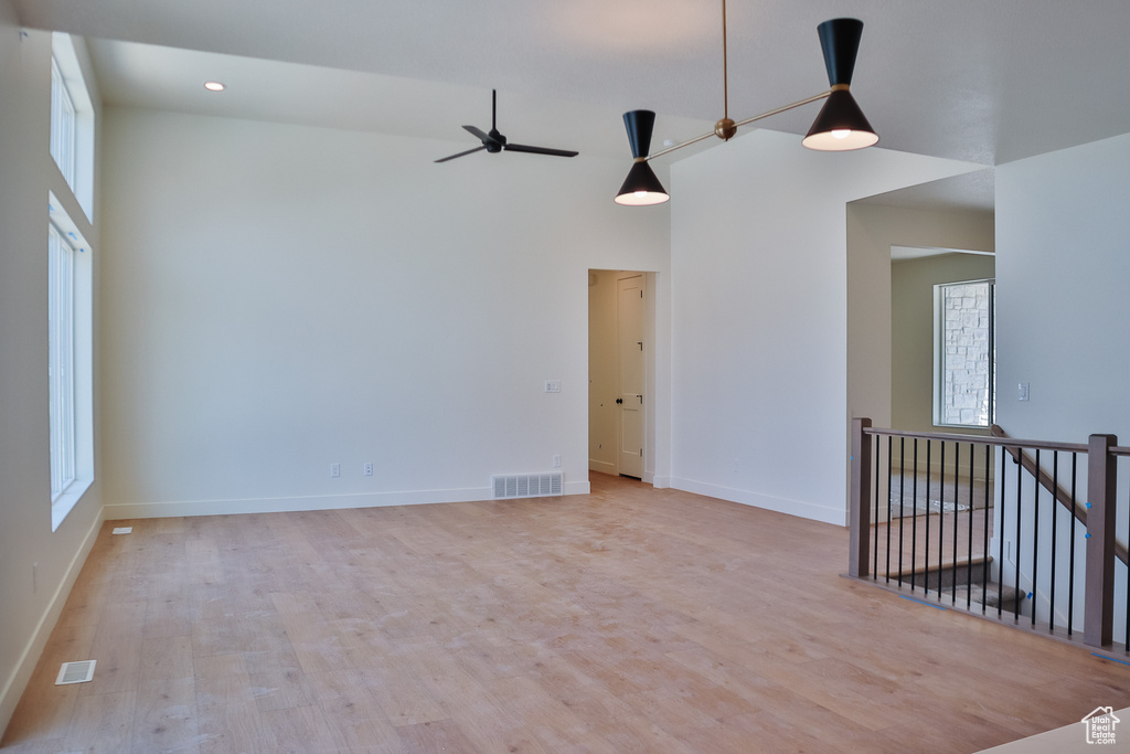 Spare room featuring light wood finished floors, baseboards, a high ceiling, a ceiling fan, and recessed lighting