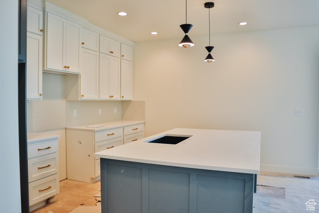 Kitchen featuring white cabinetry, a center island with sink, recessed lighting, decorative light fixtures, and light countertops