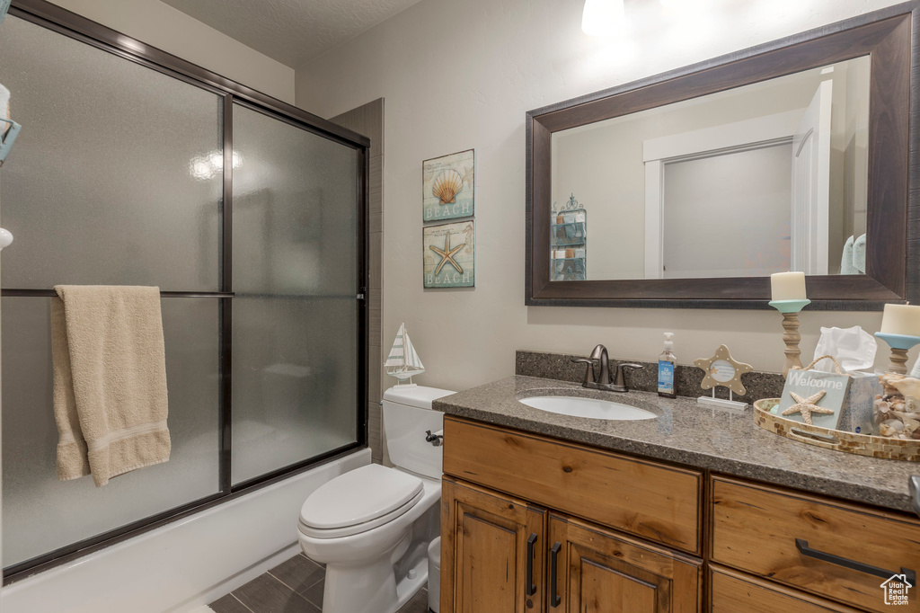 Full bathroom featuring vanity, shower / bath combination with glass door, and toilet