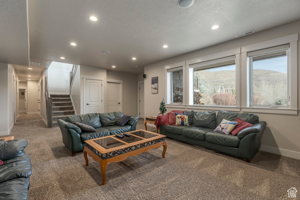 Living room with carpet flooring, recessed lighting, baseboards, stairs, and a textured ceiling