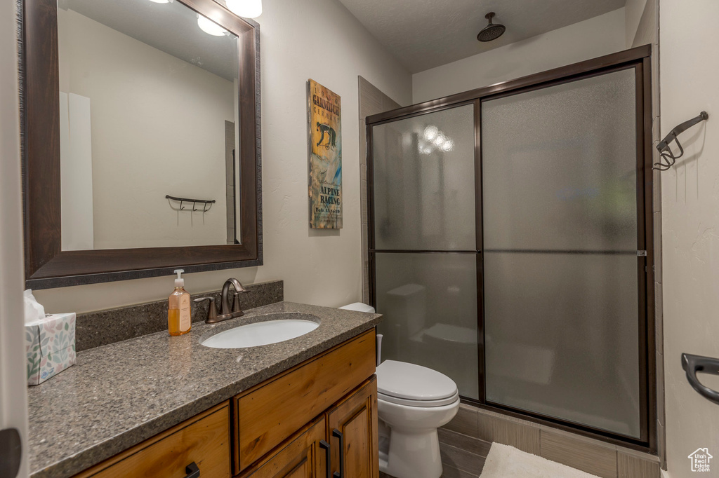 Full bath featuring a stall shower, toilet, and vanity