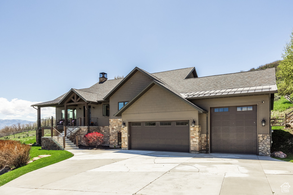 View of front of house featuring concrete driveway, a garage, a standing seam roof, stone siding, and metal roof