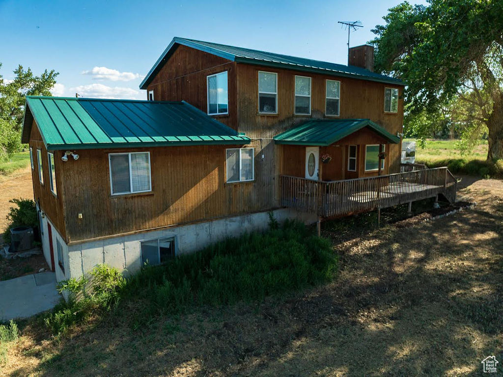 Rear view of property with a metal roof, a wooden deck, and a chimney