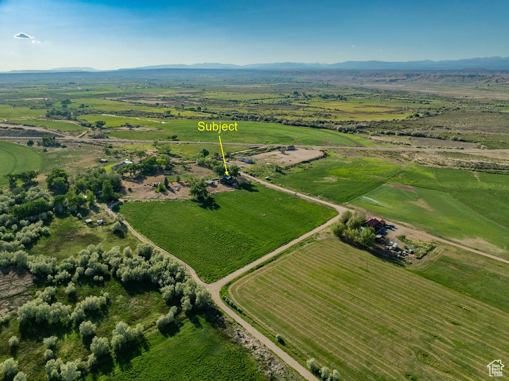 Aerial view of property and surrounding area featuring rural landscape and a mountainous background