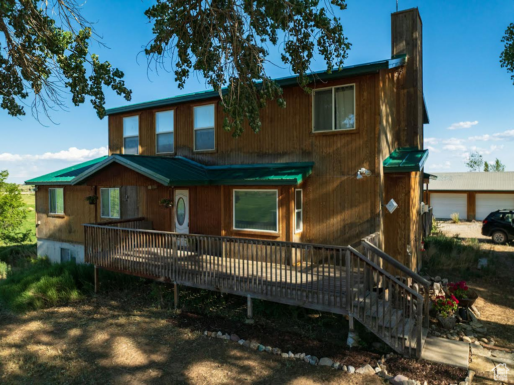 Chalet / cabin featuring a chimney, a deck, a metal roof, and a garage