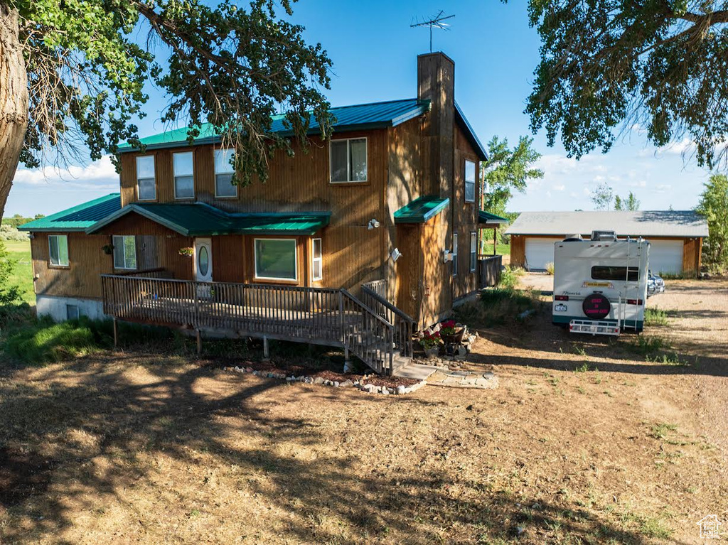 Rear view of house with a chimney, a metal roof, and a garage