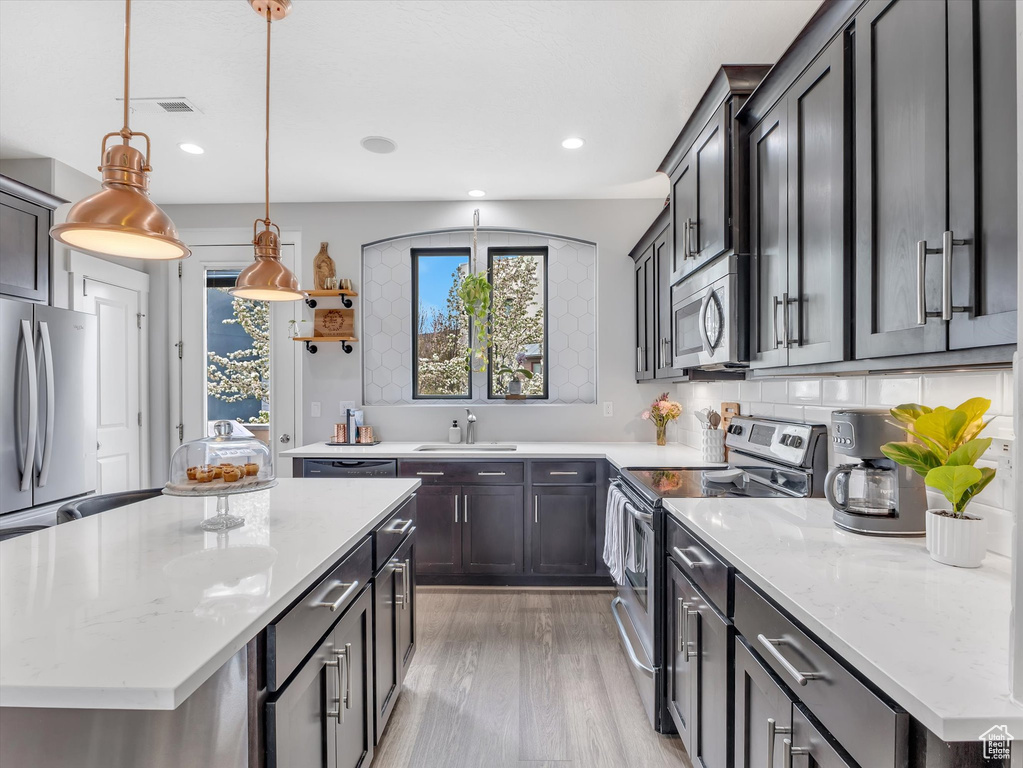 Kitchen with recessed lighting, light wood-style flooring, appliances with stainless steel finishes, and a sink
