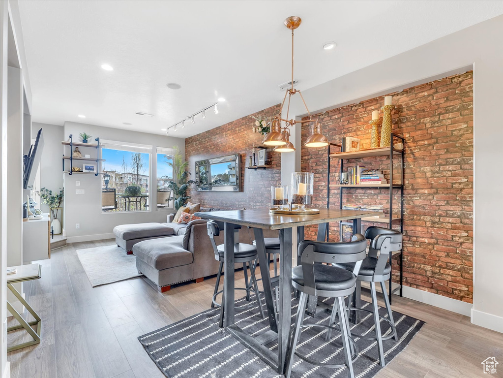 Dining space featuring light wood finished floors, baseboards, and brick wall