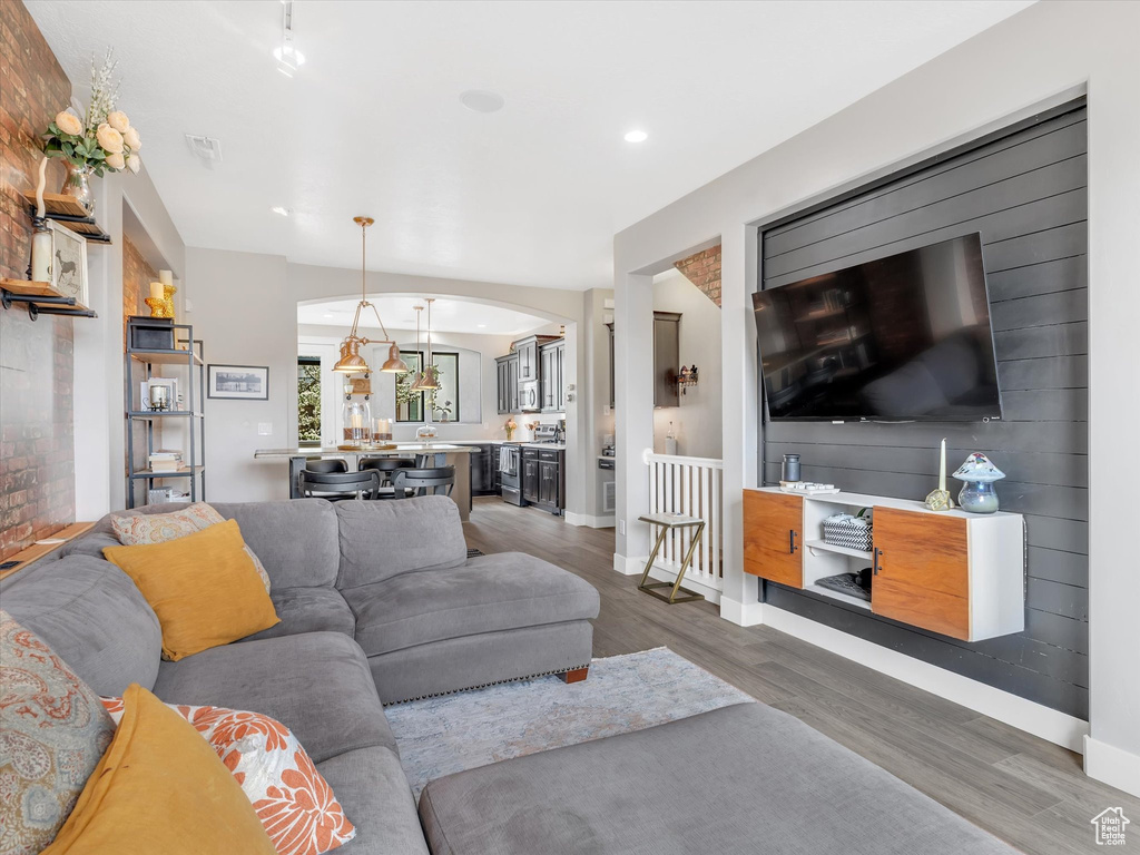 Living area featuring wood finished floors, arched walkways, baseboards, visible vents, and recessed lighting