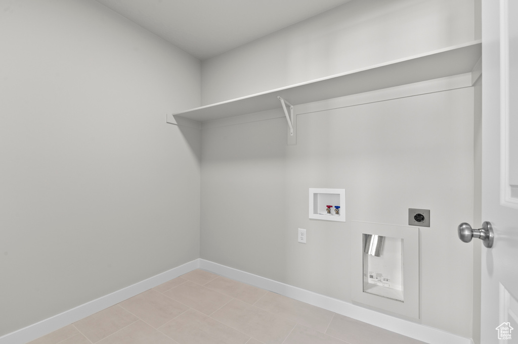 Laundry area featuring electric dryer hookup, washer hookup, baseboards, and light tile patterned floors