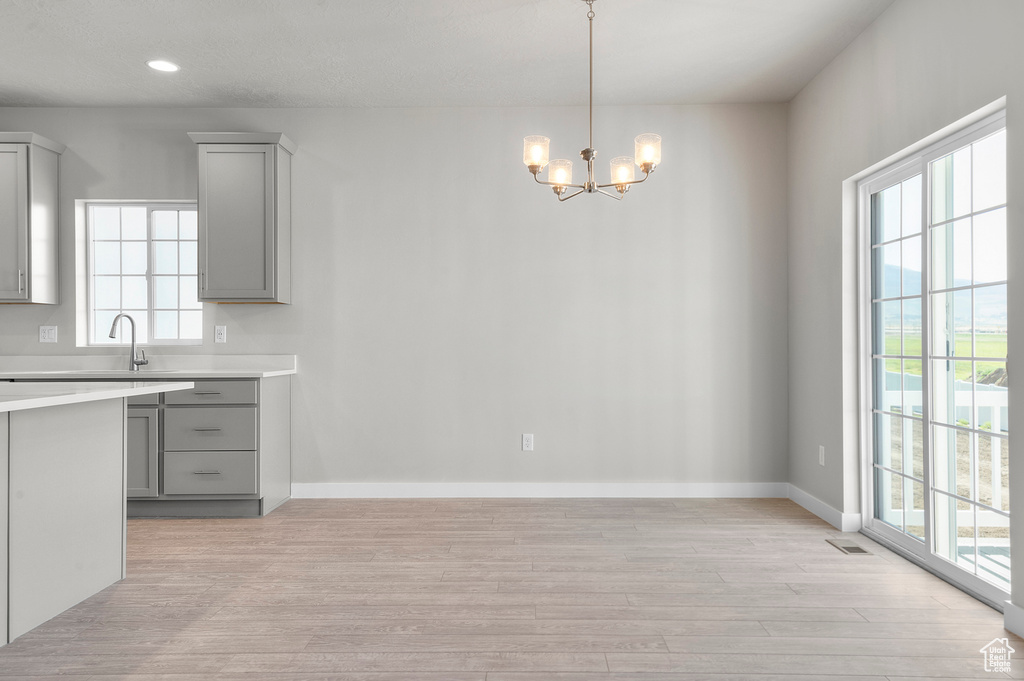 Unfurnished dining area featuring light wood-style floors, healthy amount of natural light, a chandelier, baseboards, and recessed lighting