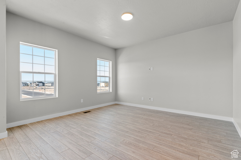 Unfurnished room featuring light wood finished floors and baseboards
