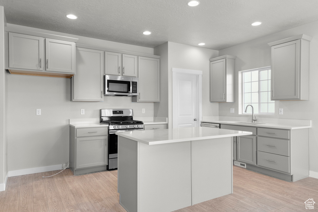 Kitchen with appliances with stainless steel finishes, a sink, gray cabinets, baseboards, and recessed lighting