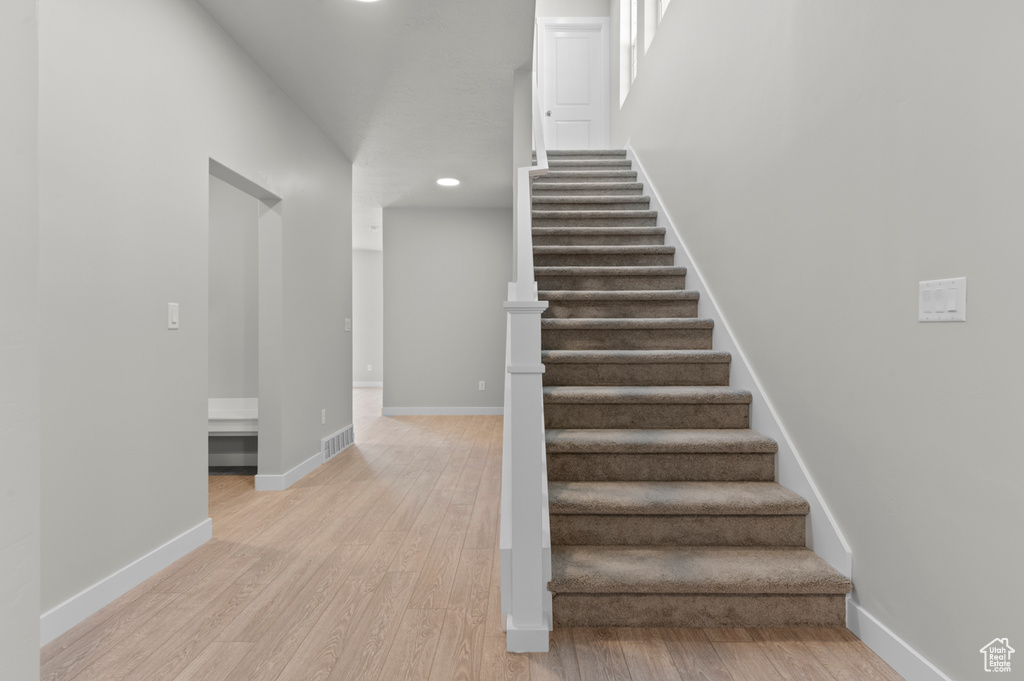 Stairway with wood finished floors, recessed lighting, and baseboards