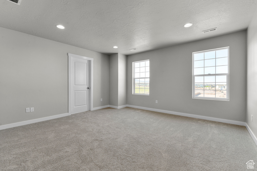 Unfurnished room with a textured ceiling, baseboards, carpet, and recessed lighting