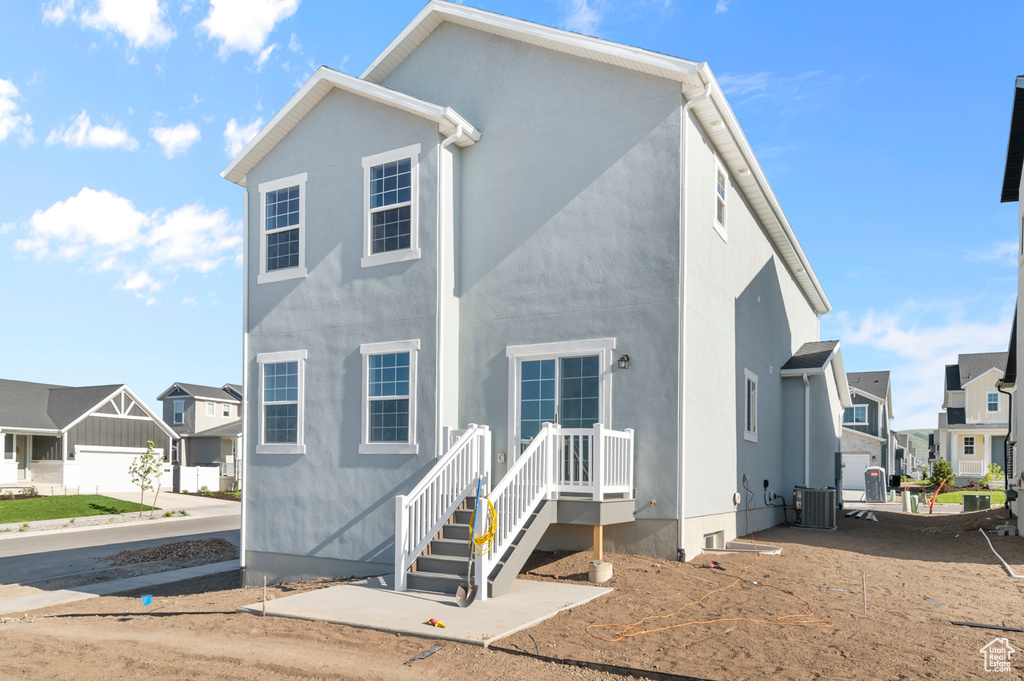 View of front of property featuring a residential view, central AC, and stucco siding