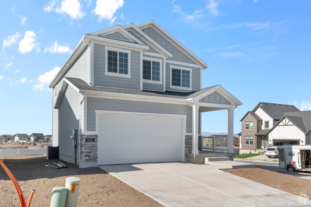 View of front of home with board and batten siding, a garage, driveway, stone siding, and a residential view