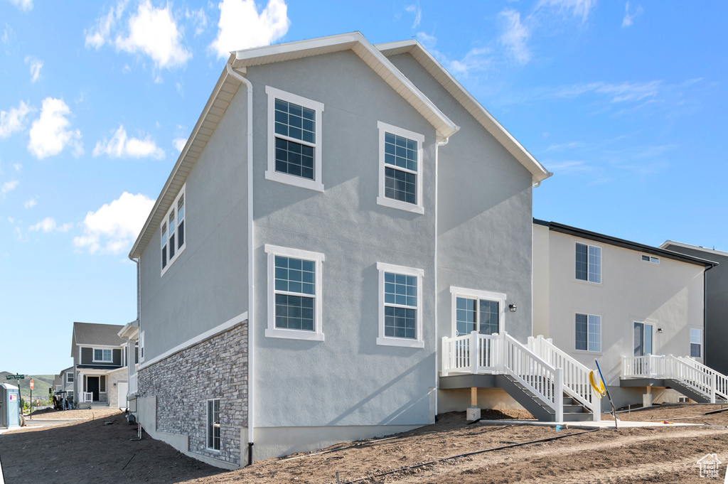 Back of house with stucco siding and stone siding