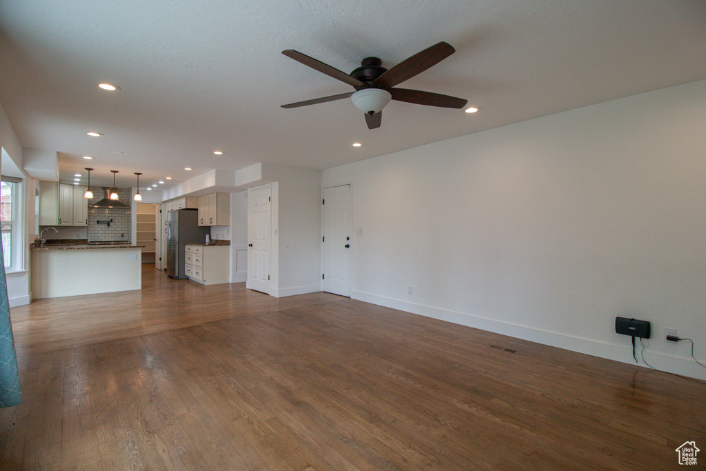 Unfurnished living room featuring recessed lighting, baseboards, dark wood-type flooring, and ceiling fan