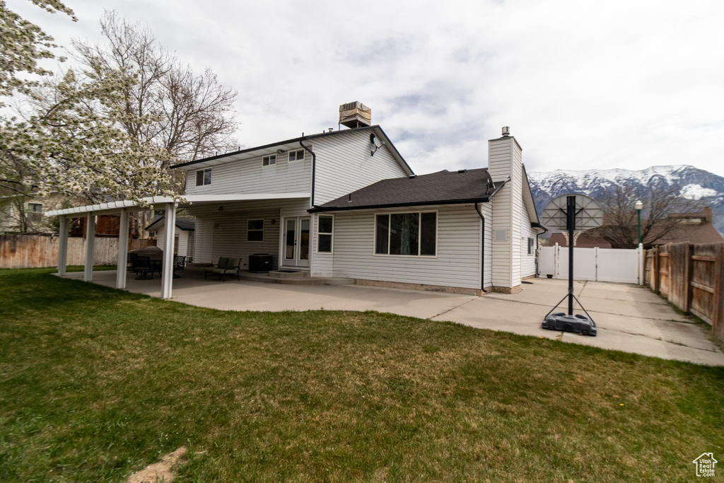 Back of house featuring a fenced backyard, a chimney, a patio, and a lawn