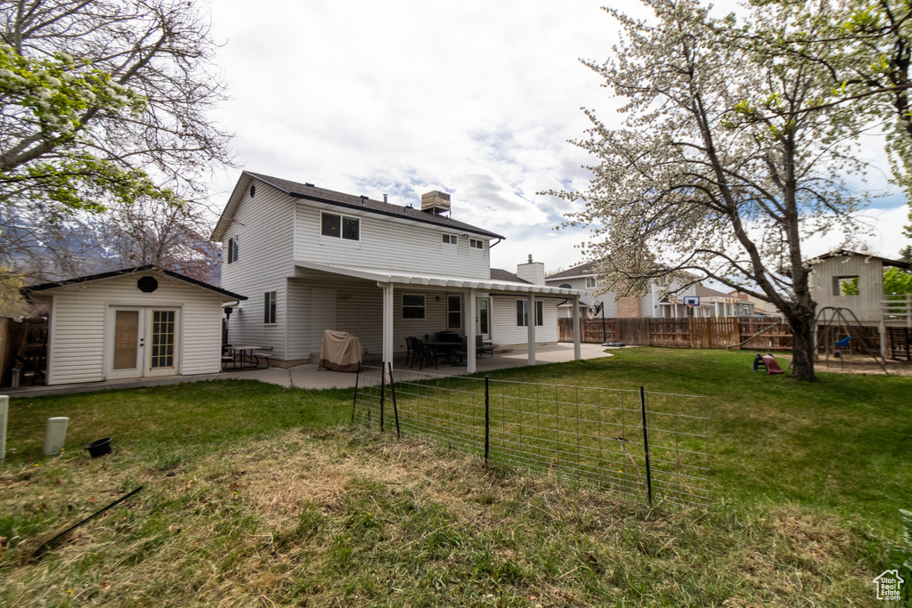 Rear view of property with a chimney, a fenced backyard, french doors, a patio, and a lawn