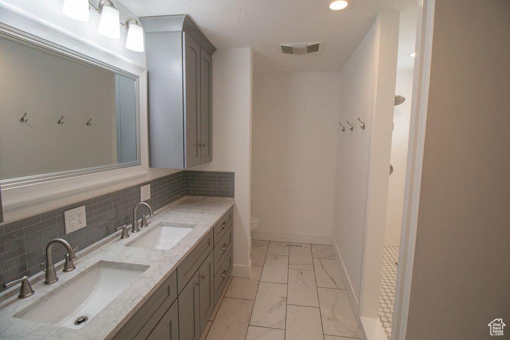 Bathroom with marble finish floor, a sink, visible vents, and double vanity