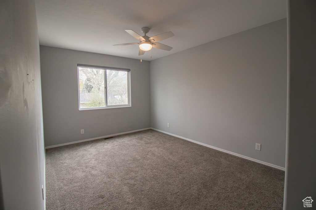 Spare room with ceiling fan, baseboards, and carpet