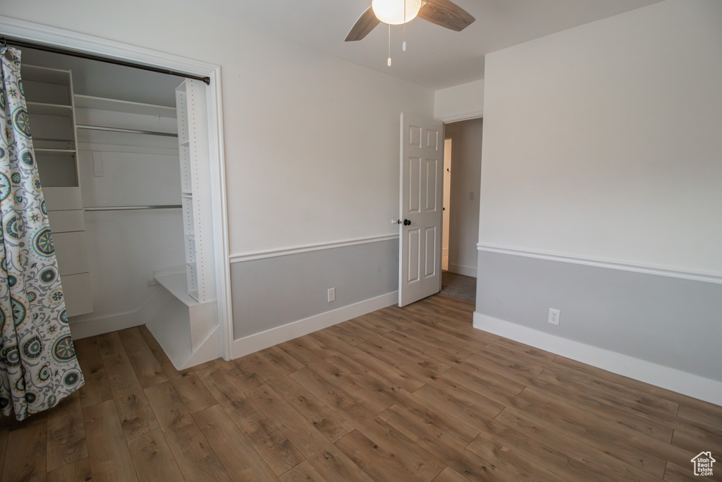 Unfurnished bedroom featuring baseboards, a ceiling fan, wood finished floors, and a closet
