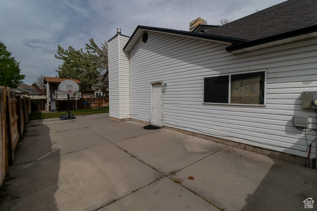 View of property exterior featuring a patio area, a chimney, and fence