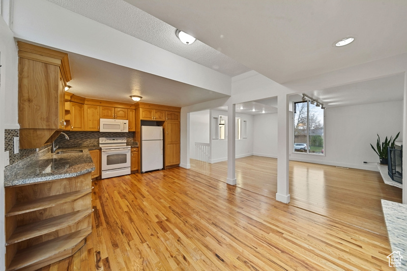 Kitchen with open shelves, a sink, white appliances, and light wood-style flooring