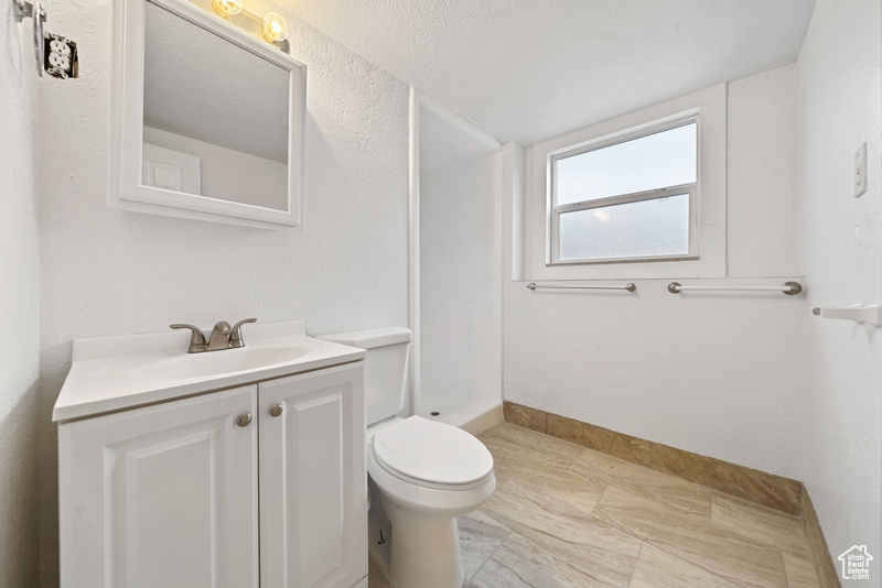 Full bathroom with toilet, walk in shower, vanity, and baseboards