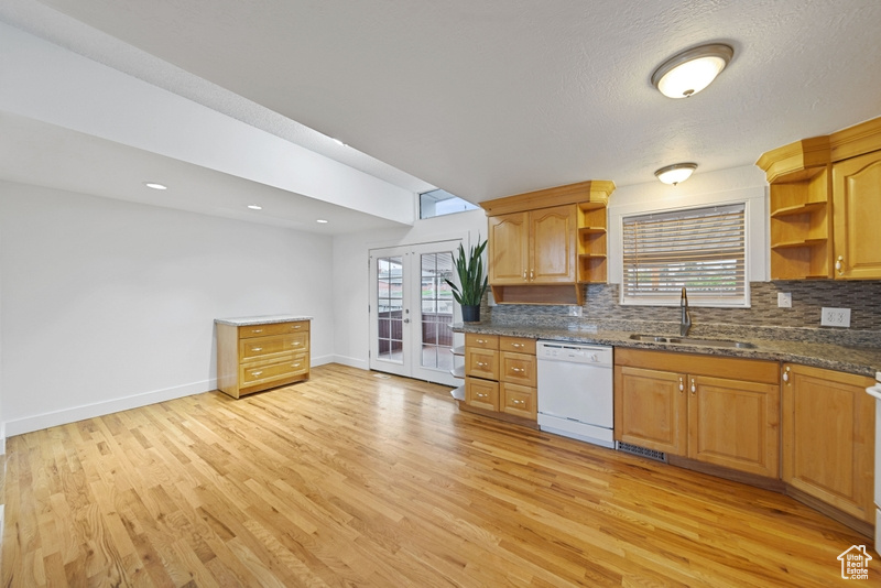 Kitchen featuring tasteful backsplash, open shelves, a sink, light wood-type flooring, and dishwasher