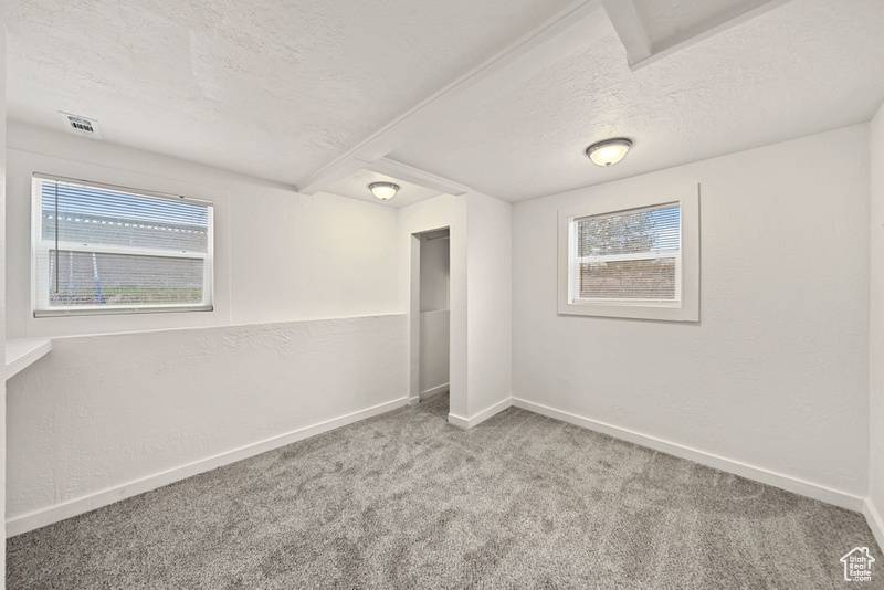 Unfurnished bedroom featuring carpet floors, a textured ceiling, baseboards, and visible vents