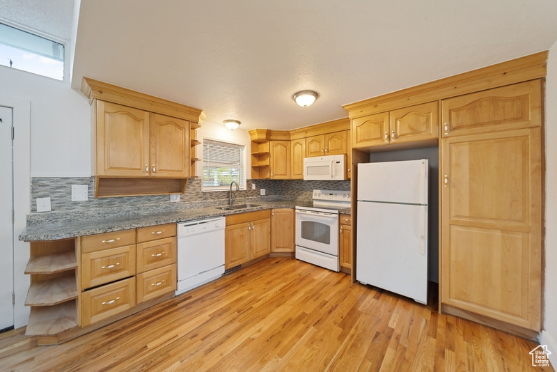 Kitchen with open shelves, light wood-style flooring, white appliances, and a sink