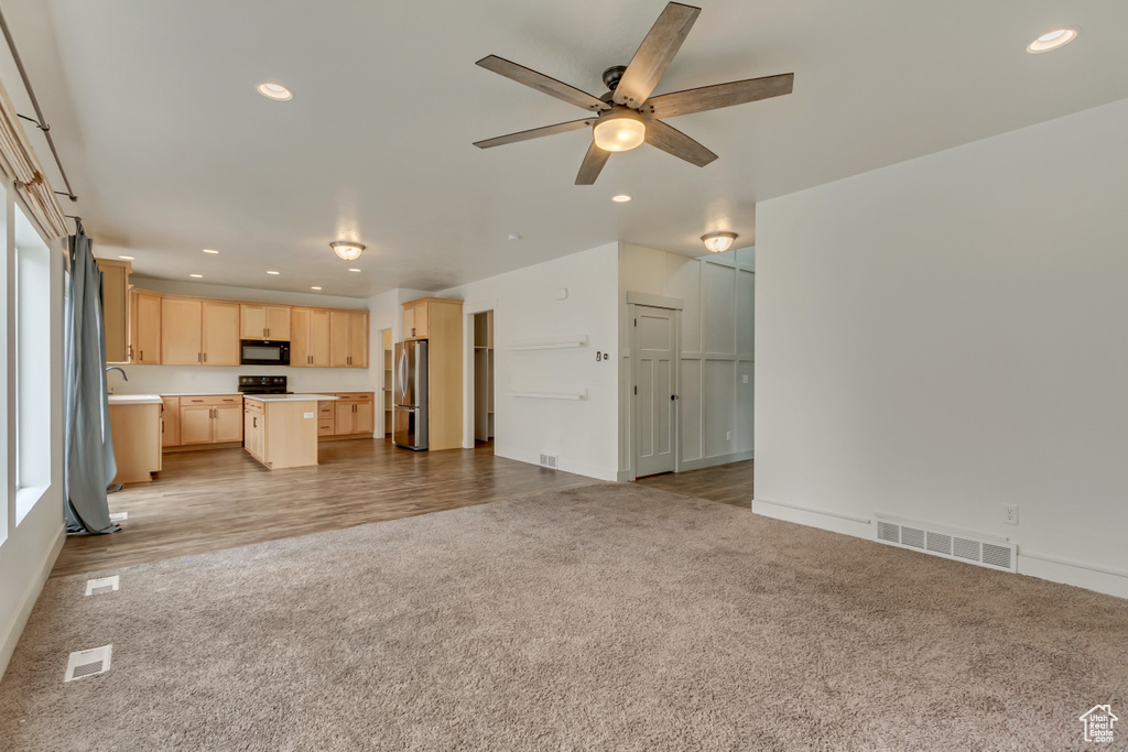 Unfurnished living room featuring a ceiling fan, a sink, light carpet, visible vents, and recessed lighting
