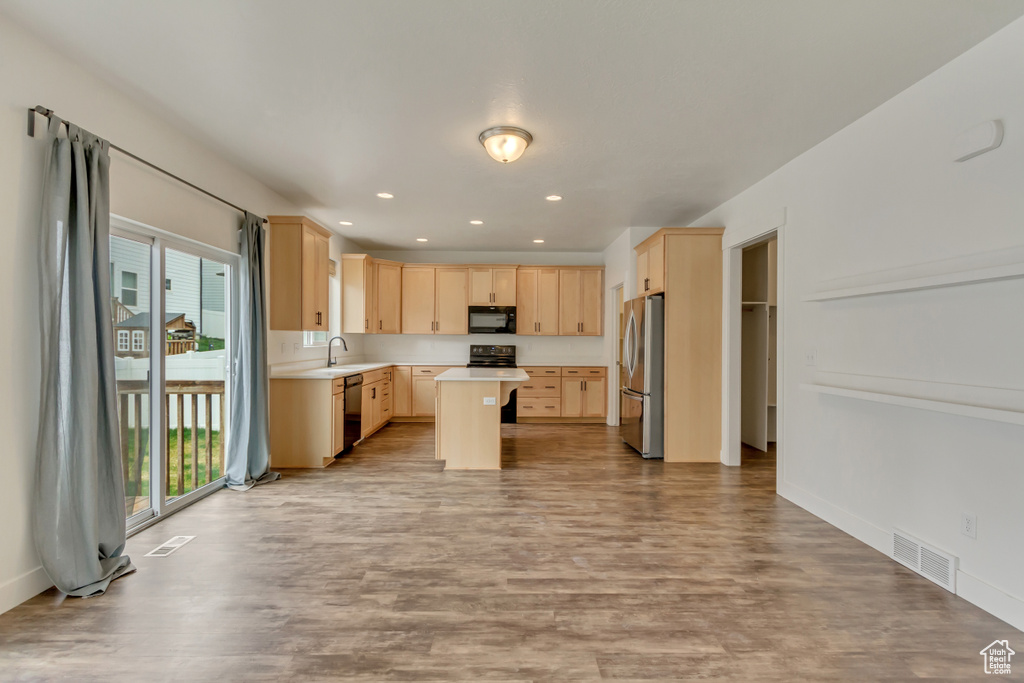 Kitchen featuring light brown cabinets, visible vents, and black appliances