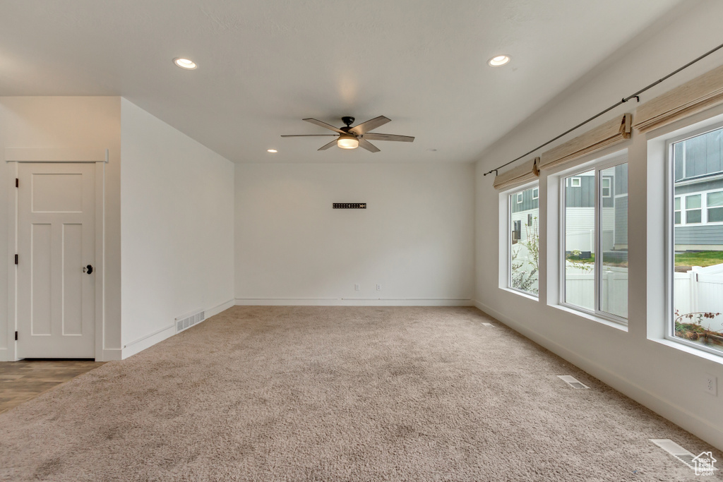 Carpeted empty room with visible vents, baseboards, recessed lighting, and ceiling fan
