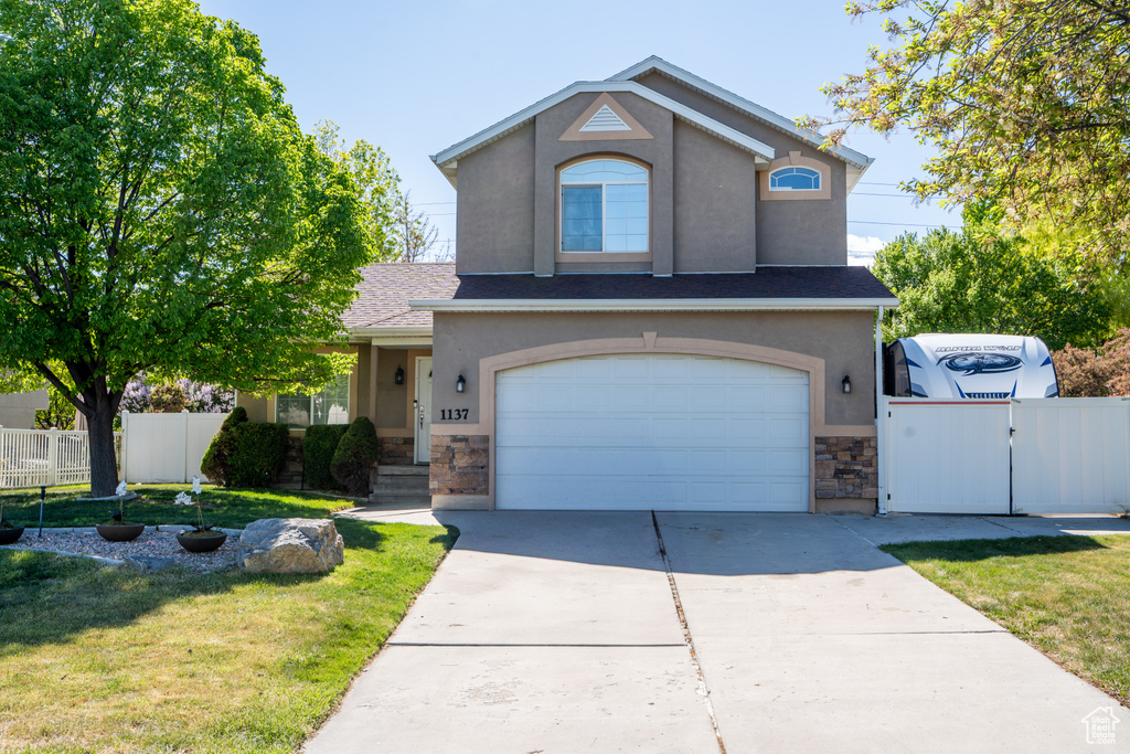 Traditional-style house with stone siding, stucco siding, a garage, and concrete driveway