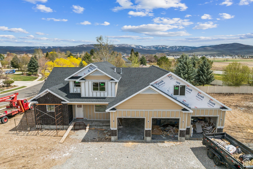 View of front of home featuring board and batten siding, driveway, a shingled roof, and a mountain view