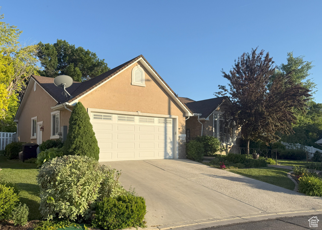 Traditional home with an attached garage, driveway, and stucco siding