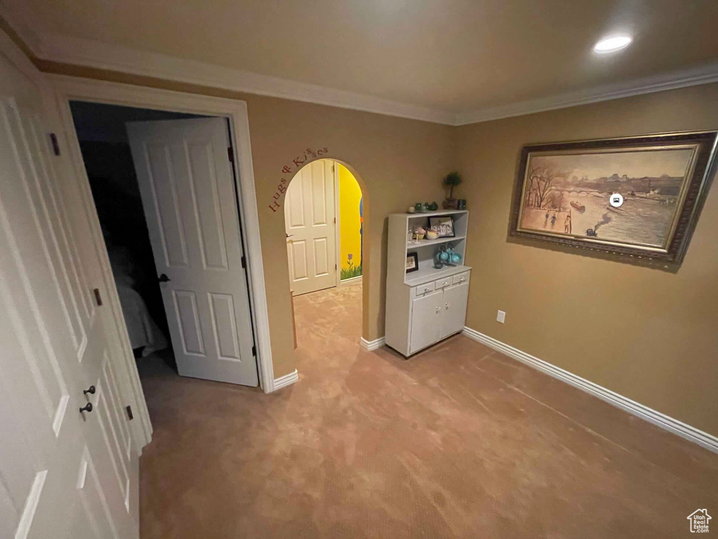 Unfurnished room featuring arched walkways, light colored carpet, ornamental molding, baseboards, and recessed lighting