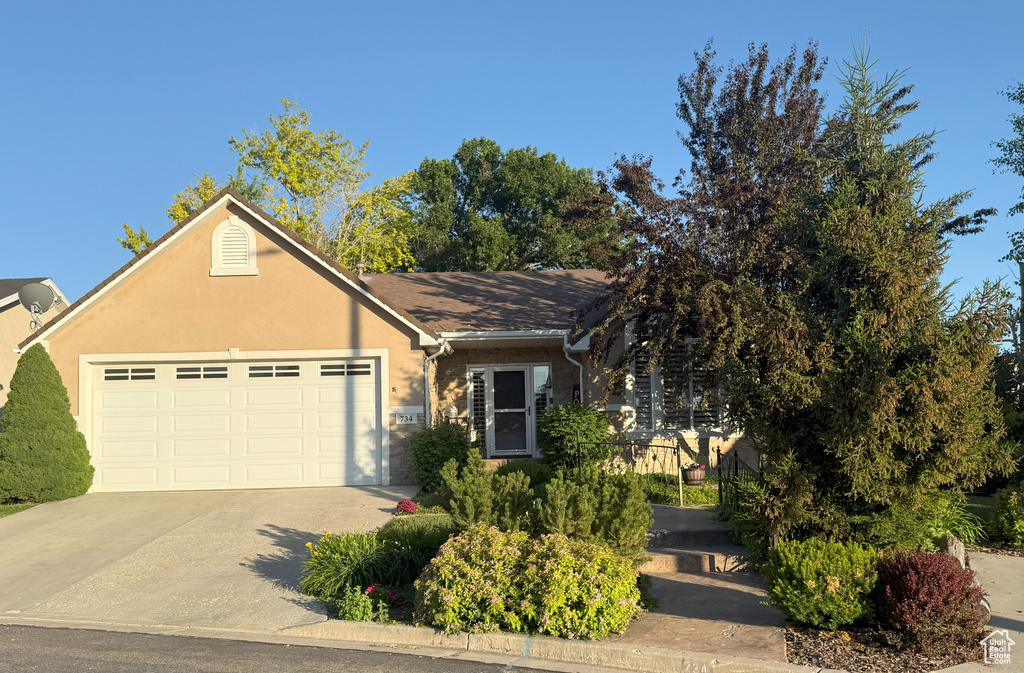 View of front facade with driveway, a garage, and stucco siding