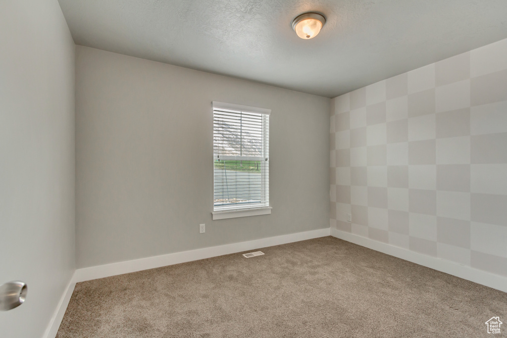Empty room with carpet floors, visible vents, and baseboards