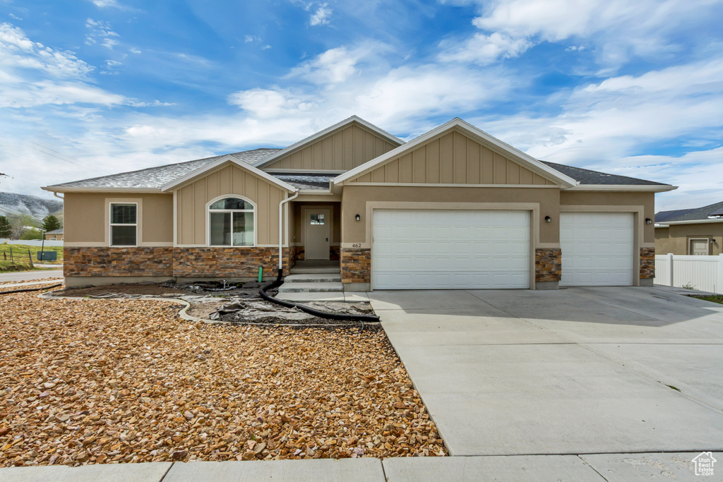 Craftsman-style house with fence, concrete driveway, stone siding, and a garage